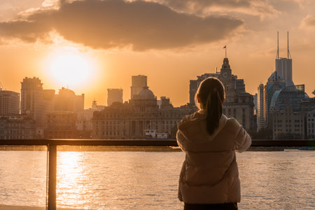 woman traveler visiting in Shanghai, China. Happy Female Tourist sightseeing Shanghai view of the bund in Lujiazui at sunset. landmark and popular for tourism attractions. Travel and Vacation conceptの写真素材
