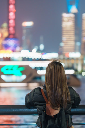 woman traveler visiting in Shanghai, China. Female Tourist with backpack sightseeing Shanghai view of Lujiazui in The Bund of Shanghai at night. landmark and popular for tourism attractionsの写真素材