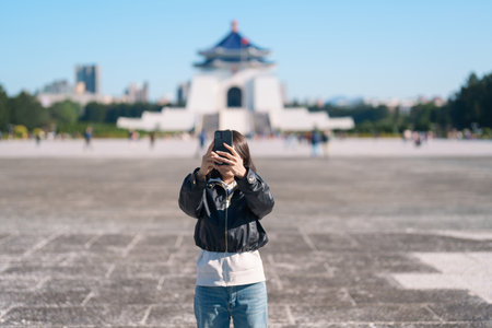 woman traveler traveling in Taiwan, female Tourist taking photo by mobile phone at National Chiang Kai shek Memorial or Hall Freedom Square, Taipei City. Popular landmark and attractionsの写真素材