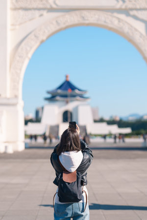 woman traveler traveling in Taiwan, female Tourist taking photo by mobile phone at National Chiang Kai shek Memorial or Hall Freedom Square, Taipei City. Popular landmark and attractionsの写真素材