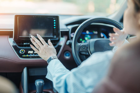 Woman hand adjusting temperature the air flowing during driving car on the road, air conditioner cooling system inside the car. Adjust, temperature and transport conceptの写真素材