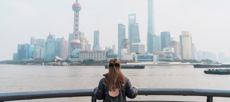 woman traveler visiting in Shanghai, China. Female Tourist with backpack sightseeing Shanghai view of Lujiazui in The Bund of Shanghai. landmark and popular for tourism attractions. Vacation conceptの写真素材