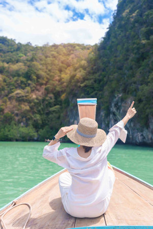 Happy Woman tourist in private longtail boat trip to koh Hong lagoon island at Krabi, Thailand. landmark, tropical destination, southeast Asia Travel, summer vacation, wanderlust and holiday conceptの写真素材