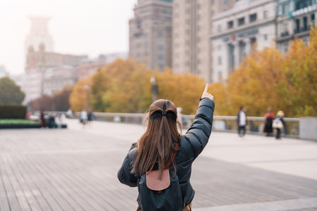 woman traveler visiting in Shanghai, China. Happy Female Tourist sightseeing Shanghai view in The Bund of Shanghai in Autumn season. landmark and popular for tourism attractions. Travel and Vacationの写真素材