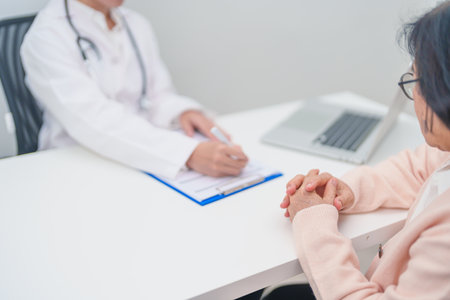 senior woman consulting with doctor in hospital. Elderly patient talking and sharing disease. Doctor listens, asking question and taking note. medical consultation and geriatric Healthcare conceptの写真素材