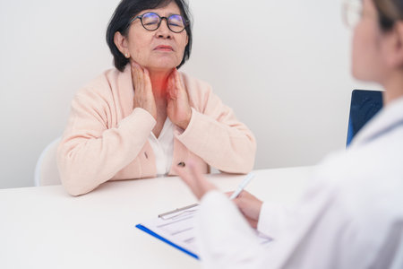 Elderly Patient having Neck pain and consulting with Doctor to Thyroid disease.Hyperthyroidism, Hypothyroidism, Hashimoto Thyroiditis, Thyroid Tumor and Cancer, Papillary Carcinoma and Medical Healthの写真素材