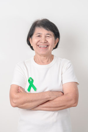 Elderly with Green Ribbon for concept of July Eye Injury Prevention month, January Glaucoma Awareness month, February Gallbladder and Bile duct and October Liver cancer. Health and world cancer dayの写真素材