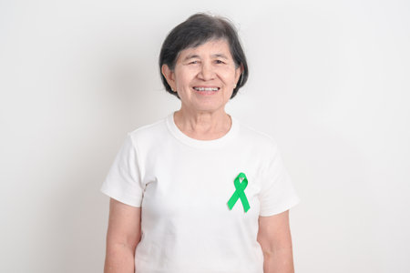 Elderly with Green Ribbon for concept of July Eye Injury Prevention month, January Glaucoma Awareness month, February Gallbladder and Bile duct and October Liver cancer. Health and world cancer dayの写真素材