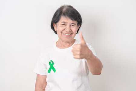 Elderly with Green Ribbon for concept of July Eye Injury Prevention month, January Glaucoma Awareness month, February Gallbladder and Bile duct and October Liver cancer. Health and world cancer dayの写真素材