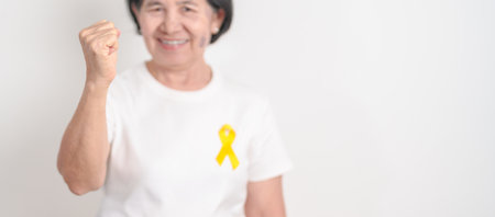 Elderly with Yellow Ribbon for concept of yellow September, Suicide prevention day, Childhood, July Sarcoma, bone cancer Awareness in children month, support survivor. Healthcare and World Cancer dayの写真素材