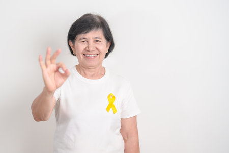 Elderly with Yellow Ribbon for concept of yellow September, Suicide prevention day, Childhood, July Sarcoma, bone cancer Awareness in children month, support survivor. Healthcare and World Cancer dayの写真素材