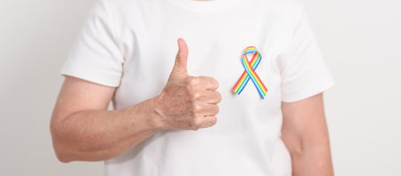 Elderly with LGBTQ Rainbow ribbon for concept of June Pride month, April Autism Awareness, All cancer Awareness, February World Cancer day, October World Hospice and Palliative care day and Survivorの写真素材