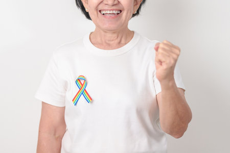 Elderly with LGBTQ Rainbow ribbon for concept of June Pride month, April Autism Awareness, All cancer Awareness, February World Cancer day, October World Hospice and Palliative care day and Survivorの写真素材