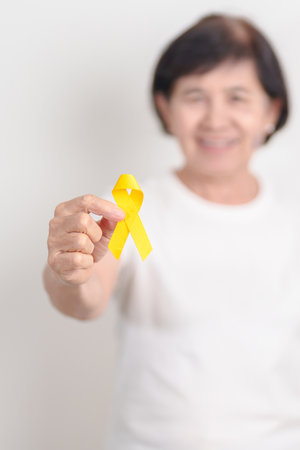Elderly with Yellow Ribbon for concept of yellow September, Suicide prevention day, Childhood, July Sarcoma, bone cancer Awareness in children month, support survivor. Healthcare and World Cancer dayの写真素材