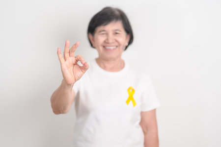 Elderly with Yellow Ribbon for concept of yellow September, Suicide prevention day, Childhood, July Sarcoma, bone cancer Awareness in children month, support survivor. Healthcare and World Cancer dayの写真素材
