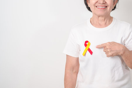 World hepatitis day awareness month, 28 July. elderly woman with Red and Yellow ribbon. Liver cancer, Jaundice, Cirrhosis, Failure, Enlarged, Hepatic Encephalopathy and Health conceptの写真素材