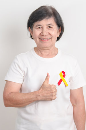 World hepatitis day awareness month, 28 July. elderly woman with Red and Yellow ribbon. Liver cancer, Jaundice, Cirrhosis, Failure, Enlarged, Hepatic Encephalopathy and Health conceptの写真素材