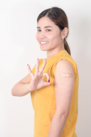 Adult Woman with bandage after received vaccine. Vaccination and Immunization for Influenza, HPV, Zoster, IPD, DTP or Diphtheria, Tetanus and Pertussis, MMR, Hepatitis B, Covid and Varicella vaccineの写真素材