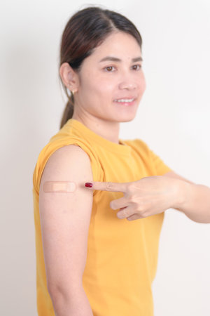 Adult Woman with bandage after received vaccine. Vaccination and Immunization for Influenza, HPV, Zoster, IPD, DTP or Diphtheria, Tetanus and Pertussis, MMR, Hepatitis B, Covid and Varicella vaccineの写真素材