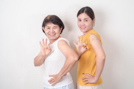 Adult and Elderly Woman with bandage after received vaccine. Vaccination and Immunization for Influenza, HPV, Zoster, IPD, DTP, Dengue, Encephalitis, Rabies, Pneumococcal Hepatitis B and Covid vaccineの写真素材