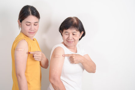 Adult and Elderly Woman with bandage after received vaccine. Vaccination and Immunization for Influenza, HPV, Zoster, IPD, DTP, Dengue, Encephalitis, Rabies, Pneumococcal Hepatitis B and Covid vaccineの写真素材