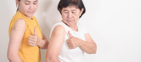 Adult and Elderly Woman with bandage after received vaccine. Vaccination and Immunization for Influenza, HPV, Zoster, IPD, DTP, Dengue, Encephalitis, Rabies, Pneumococcal Hepatitis B and Covid vaccineの写真素材