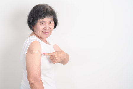 Elderly Woman with bandage after received vaccine. Vaccination and Immunization for Influenza, Herpes Zoster, Tetanus, Covid 19 booster, Dengue, Encephalitis, Rabies, Pneumococcal, IPD, RSV Vaccinesの写真素材