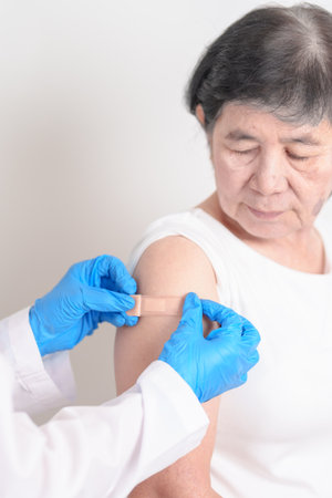 Elderly Woman with bandage after received vaccine. Vaccination and Immunization for Influenza, Herpes Zoster, Tetanus, Covid 19 booster, Dengue, Encephalitis, Rabies, Pneumococcal, IPD, RSV Vaccinesの写真素材