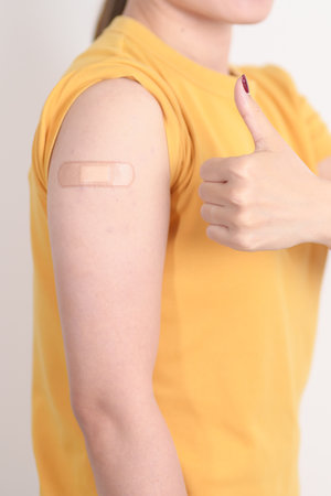 Adult Woman with bandage after received vaccine. Vaccination and Immunization for Influenza, HPV, Zoster, IPD, DTP or Diphtheria, Tetanus and Pertussis, MMR, Hepatitis B, Covid and Varicella vaccineの写真素材