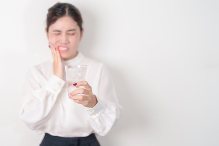 Business woman having toothache and pain after drink ice water for concept of Teeth Sensitive to Cold, Tooth Decay and Gum Disease, Grinding Teeth and Stress, Exposed Nerve Roots, Crack and Recedingの写真素材