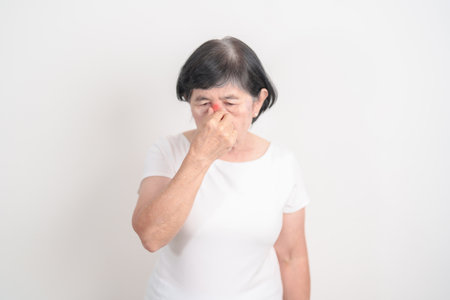 Elderly  Woman having Nose pain for concepts of Nose disease, Common Cold, Influenza, Flu, Covid 19, Respiratory Infection, Sinusitis, Allergic Rhinitis, Asthma, Allergy, Dry nose Anosmia and Healthの写真素材