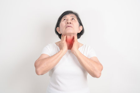 elderly Woman checking Thyroid gland disease. Hand holding Neck pain and Sore Throat. Hyperthyroidism, Hypothyroidism, Hashimoto Thyroiditis, Thyroid Tumor and Cancer, Postpartum, Papillary Carcinomaの写真素材