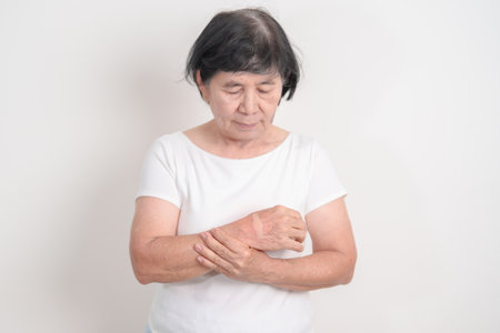 Elderly Woman having wrist pain with Medicated pain relief patch plaster for Carpal Tunnel Syndrome, Wrist Tendinitis, muscle ache, De Quervain s tenosynovitis, Hand Osteoarthritis and Senior healthの写真素材
