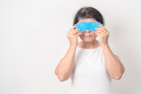 Elderly Woman with cold Eye Mask for concepts of Eye disease, Dry, Pain and Irritation eyes, Cataract, Glaucoma, Age Related Macular Degeneration, Conjunctivitis, World Glaucoma day and healthの写真素材