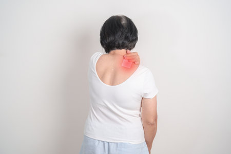 Elderly Woman having Shoulder Pain with Medicated pain relief patch plaster for Muscle Inflammation and Sprain, Myofascial ache syndrome and Fibromyalgia, Shoulder Myalgia and Scapular Tightnessの写真素材