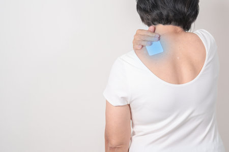 Elderly Woman having Shoulder Pain with Medicated pain relief patch plaster for Muscle Inflammation and Sprain, Myofascial ache syndrome and Fibromyalgia, Shoulder Myalgia and Scapular Tightnessの写真素材