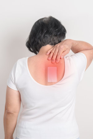 Business woman having back ache with Medicated pain relief patch plaster for Back Muscle Strain, Scapular Muscle Tightness, Piriformis Syndrome, Osteoporosis, Spinal Compression and Health careの写真素材