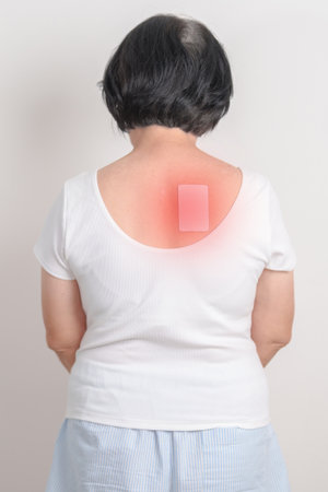 Business woman having back ache with Medicated pain relief patch plaster for Back Muscle Strain, Scapular Muscle Tightness, Piriformis Syndrome, Osteoporosis, Spinal Compression and Health careの写真素材