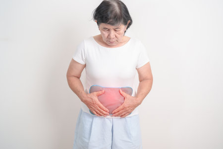 Elderly woman having abdomen aches with Hot Water Bottle Bag for Pain Relief for Stomach pain, digestion with constipation or Diarrhea from food poisoning, Stomachache and health care conceptsの写真素材