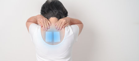 Business woman having back ache with Medicated pain relief patch plaster for Back Muscle Strain, Scapular Muscle Tightness, Piriformis Syndrome, Osteoporosis, Spinal Compression and Health careの写真素材