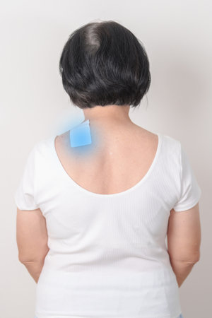 Elderly Woman having Shoulder Pain with Medicated pain relief patch plaster for Muscle Inflammation and Sprain, Myofascial ache syndrome and Fibromyalgia, Shoulder Myalgia and Scapular Tightnessの写真素材