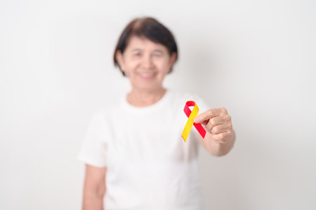 World hepatitis day awareness month, 28 July. elderly woman with Red and Yellow ribbon. Liver...