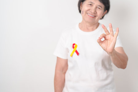 World hepatitis day awareness month, 28 July. elderly woman with Red and Yellow ribbon. Liver cancer, Jaundice, Cirrhosis, Failure, Enlarged, Hepatic Encephalopathy and Health conceptの写真素材