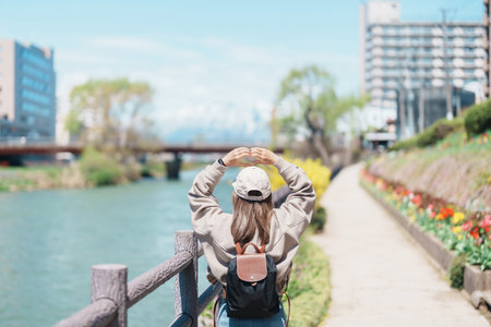 Woman tourist sightseeing Iwate mountain and Kitakami river with flowers in Spring, happy traveler travel in Morioka city, Iwate prefecture, Japan. famous Landmark Travel and Vacation destinationの写真素材