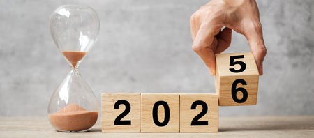 hand flipping block 2025 to 2026 text with hourglass on table. Resolution, time, plan, goal, motivation, reboot, countdown  and New Year holiday conceptsの写真素材