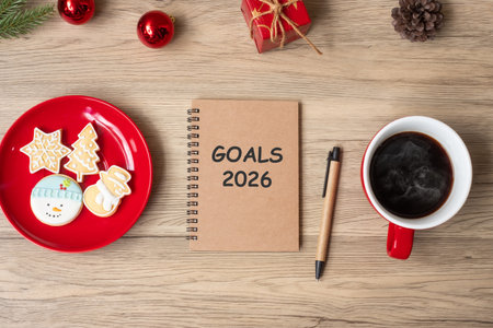 2026 GOAL with notebook, black coffee cup, Christmas cookies and pen on wood table. Xmas, Happy New Year, Resolution, To do list, Strategy and Plan conceptの写真素材
