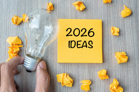 2026 Idea words on yellow note and crumbled paper with Businessman holding lightbulb on wooden table background. New Year New Start Creative, Innovation, Imagination, Resolution and Goal conceptの写真素材