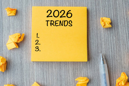 2026 Trends word on yellow note with pen and crumbled paper on wooden table background. New Year New...