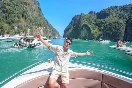 man tourist on boat trip, happy traveller relaxing at Pileh lagoon on Phi Phi island, Krabi, Thailand. Exotic landmark, destination Southeast Asia Travel, summer vacation and holiday conceptの写真素材
