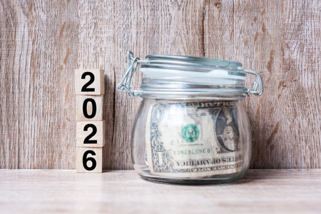 2026 Happy New Year with US dollar money glass American on wood table background. business, investment, retirement planning, finance, Saving and New Year Resolution conceptsの写真素材